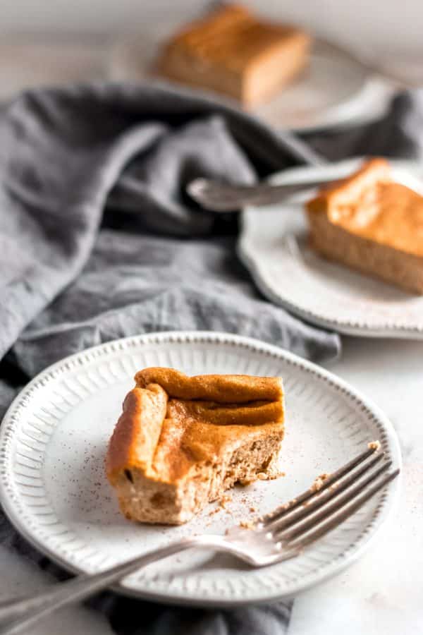 three servings of pumpkin cheesecake bars on a saucer one of which is half-eaten