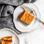four servings of pumpkin cheesecake bars on top of a marble counter with a gray table napkin spread unevenly