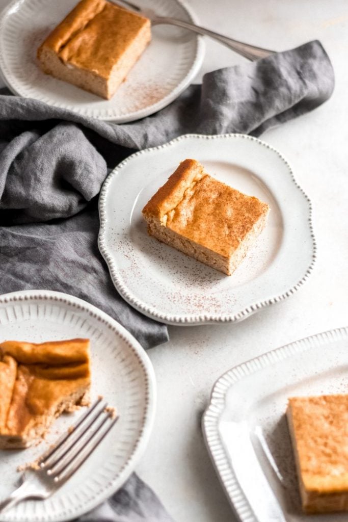 slightly angled shot of four pumkin cheesecake bars served in individual ceramic saucers on top of a marble counter