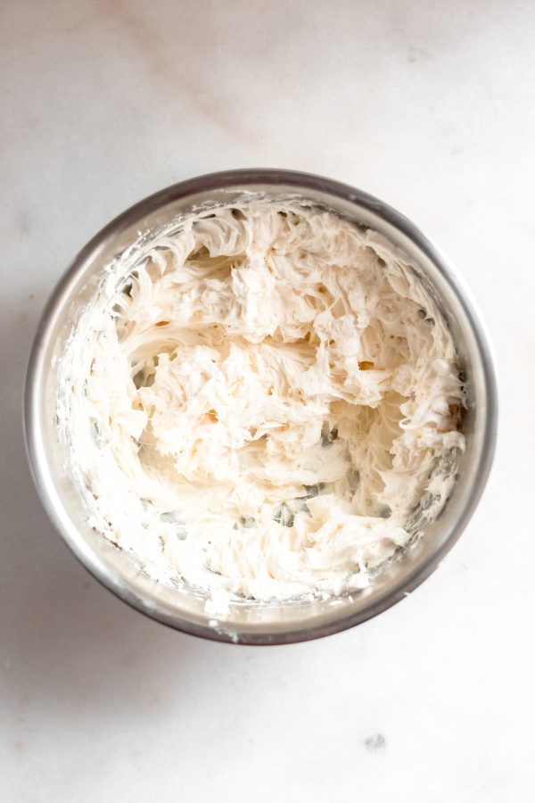 softened cream cheese mixed using an electric mixer in a stainless steel bowl