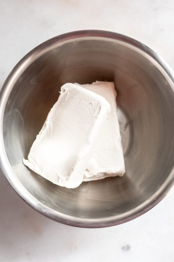 two blocks of cream cheese in a large stainless steel mixing bowl