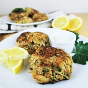 white Plate of low carb crab cakes with lemon and sauce