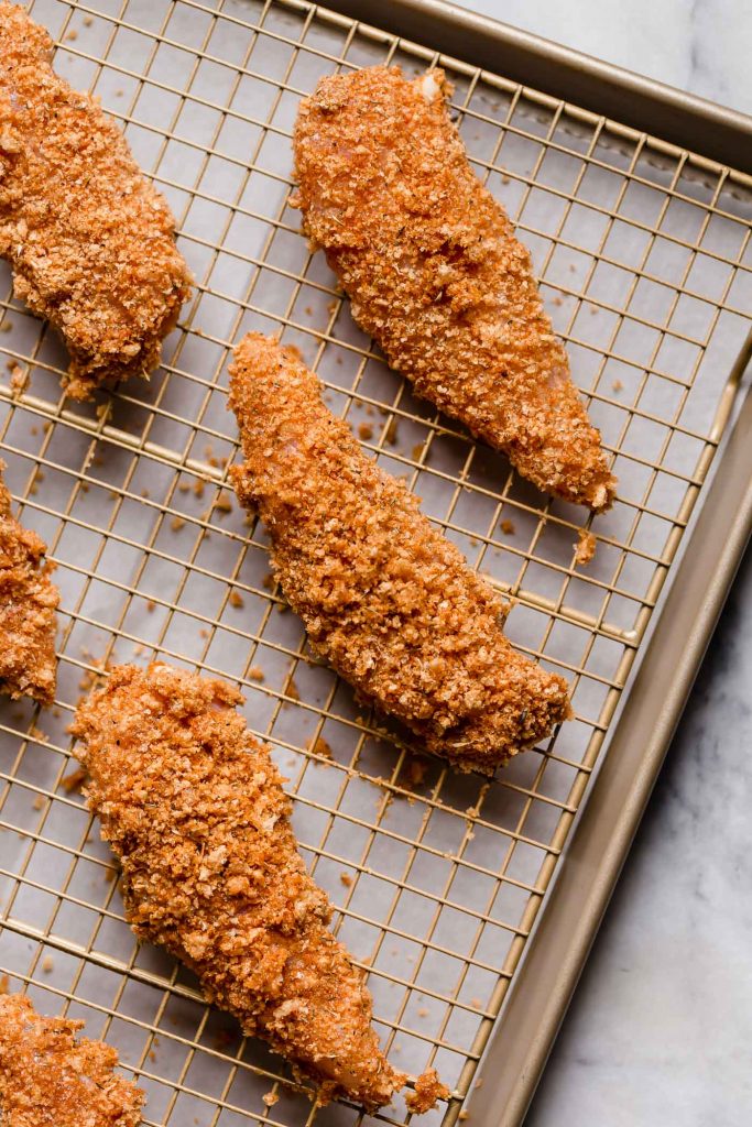 crushed pork rind-covered chicken tenders on a baking rack