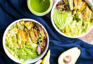 two servings of Easy Sheet Pan Taco Bowls beside a halved avocado