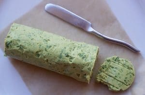 Herb Bone Marrow Butter on top of parchment paper beside a butter knife