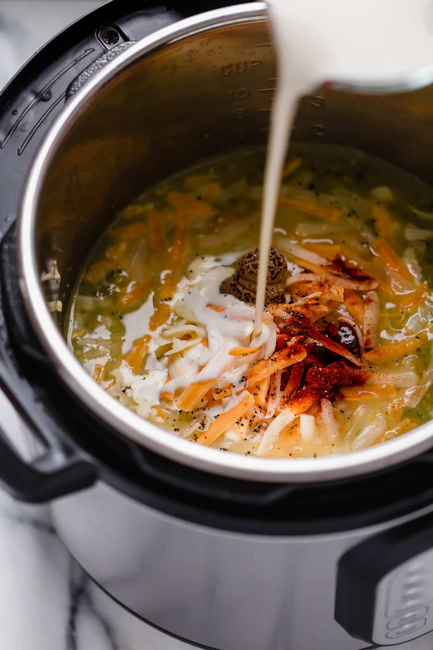 heavy cream poured into instant pot that has broth with cooked broccoli cheese and spices