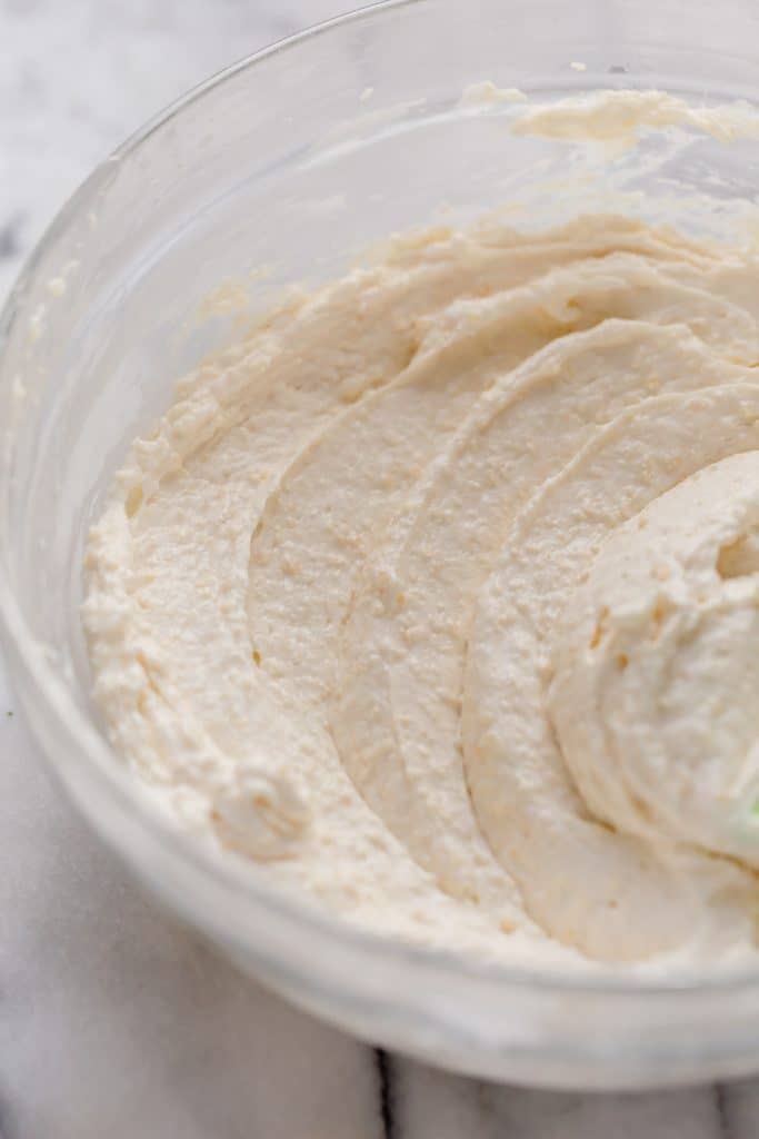 cream cheese, parmesan cheese, mayonnaise, and sour cream mixture in a clear glass bowl