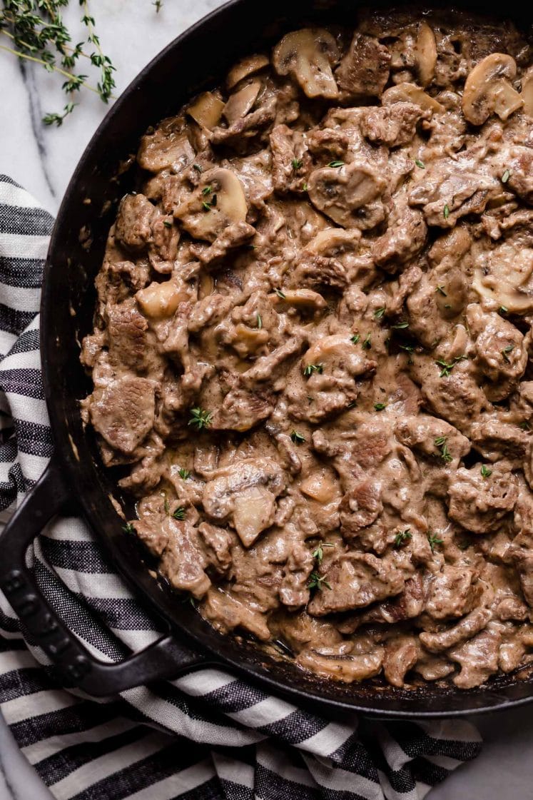 chopped seasoned and cooked beef with sliced button mushrooms and stirred-in sour cream and mayonnaise in a large cast iron sauce pan