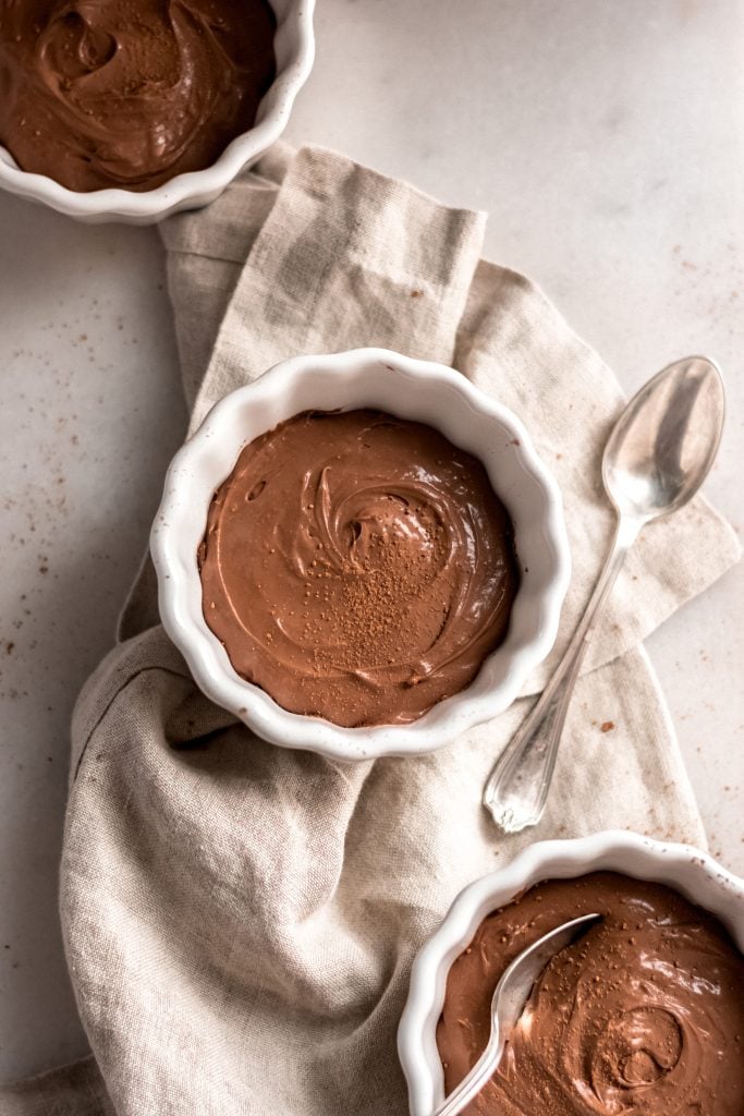 three servings of keto chocolate pudding in separate bowls on a table napkin