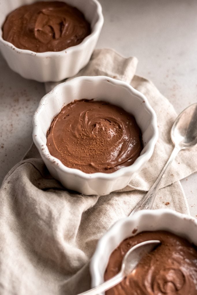 three bowls of keto chocolate pudding with a spoon in one of them