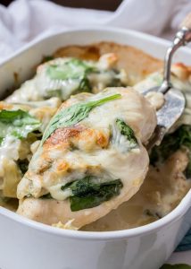 Spinach artichoke smothered chicken in a casserole dish