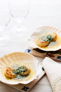 Keto Scallops with Garlic and Herb Butter served in their shells beside drinking glasses