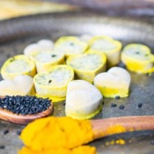 Anti-Inflammatory MCT Fat Bombs shaped into hearts with a spoon of turmeric and black sesame seeds