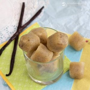 Easy Vanilla Fat Bombs in a small glass with vanilla bean sticks paper napkins and a doily