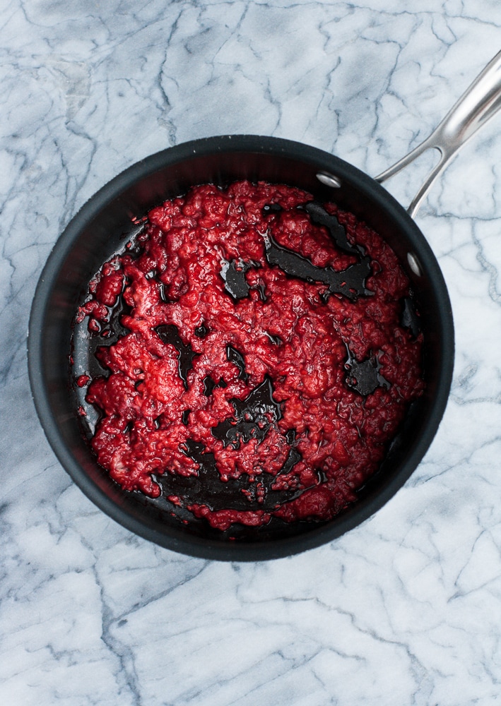 heated raspberries mashed in a saucepan over medium heat
