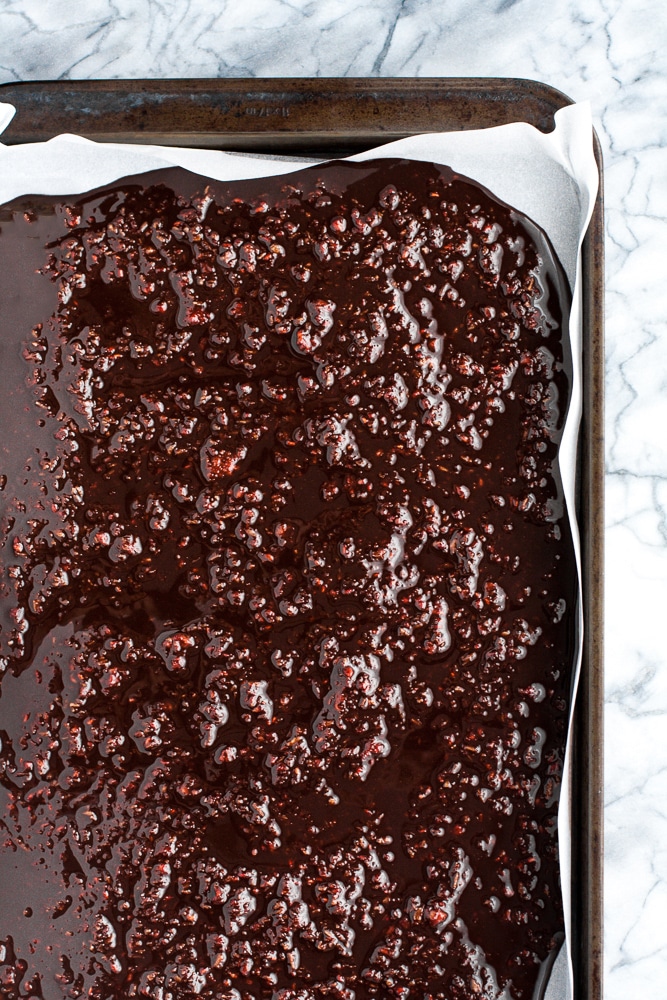 melted dark raspberry chocolate mixture poured onto a baking sheet lined with parchment paper