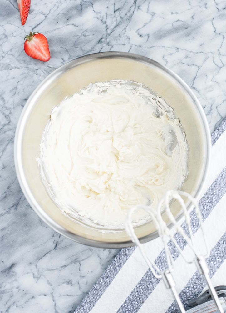 butter and cream cheese mixed using an electric mixer in a stainless steel mixing bowl
