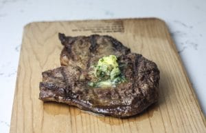 Grilled Ribeye with Garlic and Herb Compound Butter on a wooden chopping board