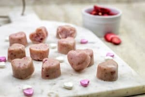 Paleo Strawberry Heart Fudge on a marble cheese board with white and pink candy hearts