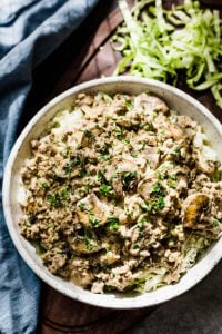 low carb beef stroganoff on a bowl beside a blue table napkin