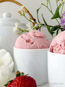 Low Carb Sugar Free Strawberry Buttermilk Ice Cream in 2 serving cups beside a strawberry and a teapot