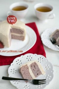 Strawberry Coconut Flour Mug Cake sliced and served in a ceramic saucer with a fork and two tea cups in the background