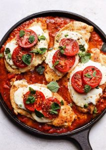 top view of keto chicken parmesan with fresh tomato slices in a skillet