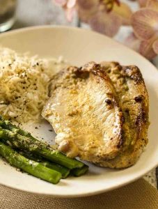 honey mustard pork chops on a round plate with asparagus and rice