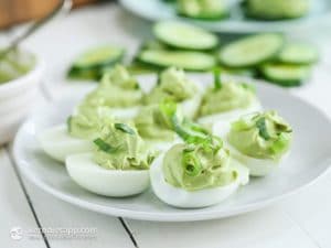 avocado and egg fat bombs on a plate with sliced cucumbers in the background
