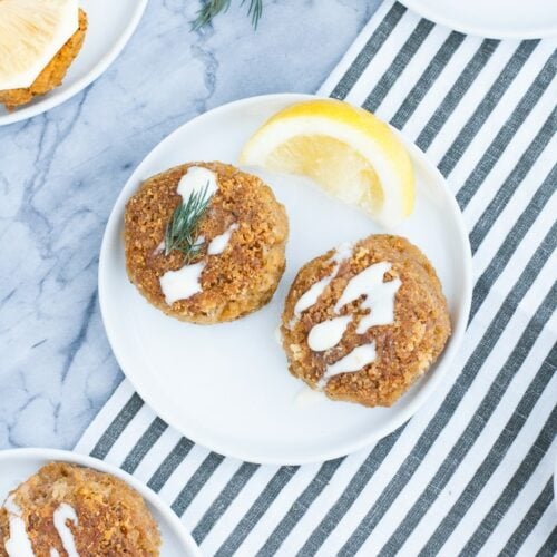 overhead shot of 2-serving low carb tuna cakes on a white plates beside a wedge of lemon