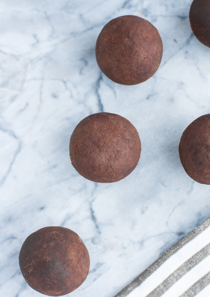 Chocolate Truffle Fat Bombs rolled into balls on a marble kitchen counter