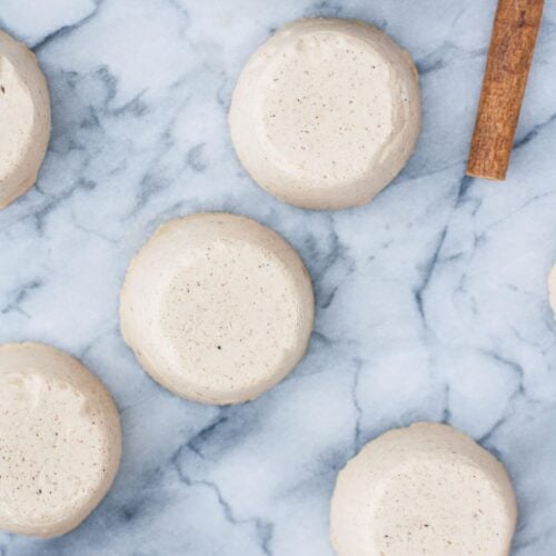 Chai Latte Fat Bombs on a marble counter beside a bowl of ingredients and a stick of cinnamon