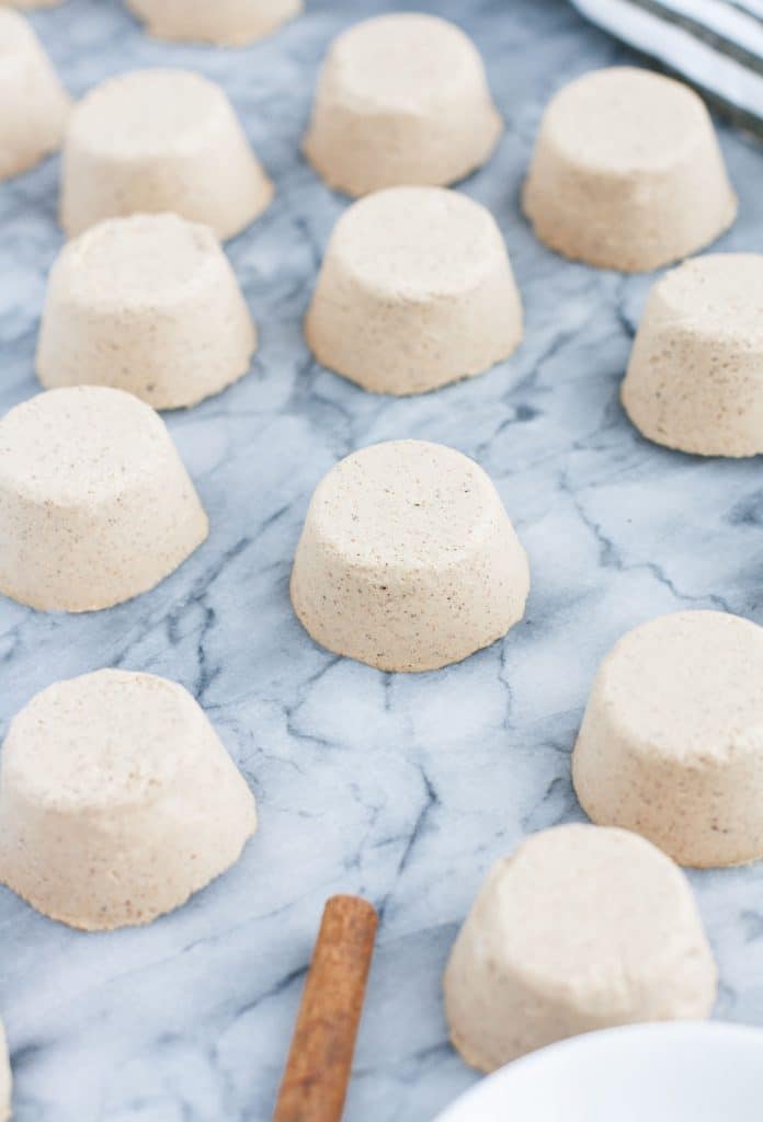 chai latte fat bombs on a marble kitchen counter with a cinnamon stick
