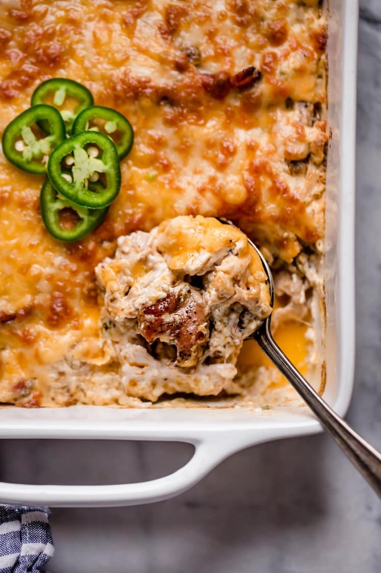 Jalapeño Popper Chicken Casserole in a baking dish scooped with spoon