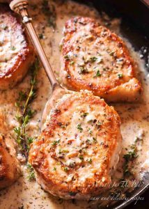 creamy low carb pork chops in a cast iron skillet with a gold spoon