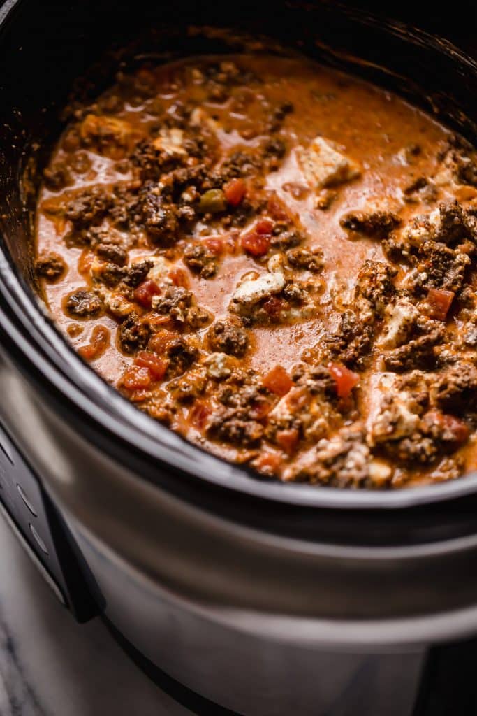 browned ground beef, cubed cream cheese, canned tomatoes with green chiles, chili powder, cumin, paprika, pepper, salt, and red pepper flakes with beef broth and red pepper flakes stirred together in a slow cooker