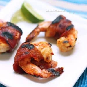 keto bacon wrapped barbecue shrimps with lime wedges on a square plate