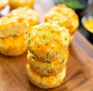 cheesy cauliflower muffins stacked on a cheeseboard