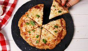 best keto chicken parmesan pizza on a round stone with picnic cloth