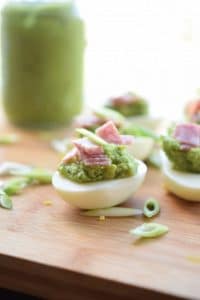 pesto deviled eggs on a wooden board