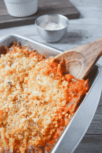 keto chicken parmesan casserole in a metal dish with a wooden spoon