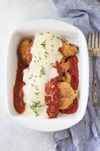 low carb chicken parmesan in a white dish with striped cloth and rustic fork