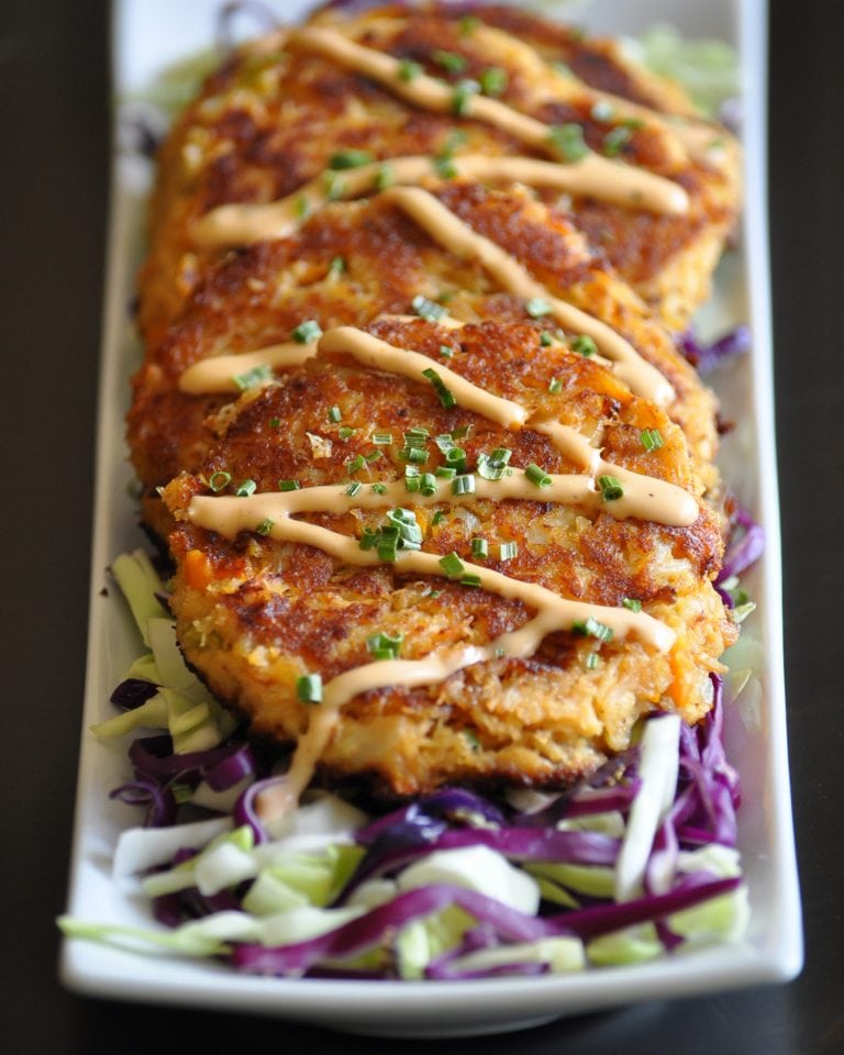 cajun crab cakes on a serving plate surrounded by sliced cabbage