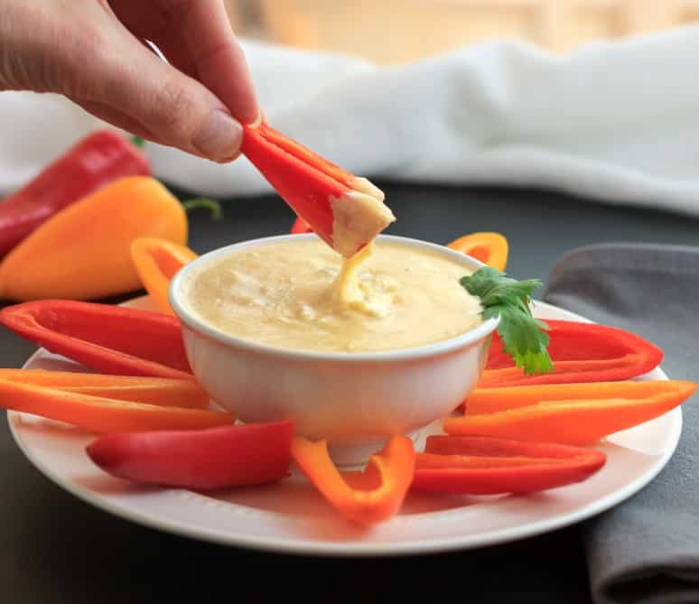 mini bell pepper being dipper into chili queso dip