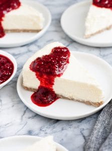 slices of nut free keto cheesecake drizzled with raspberry sauce served in small white plates