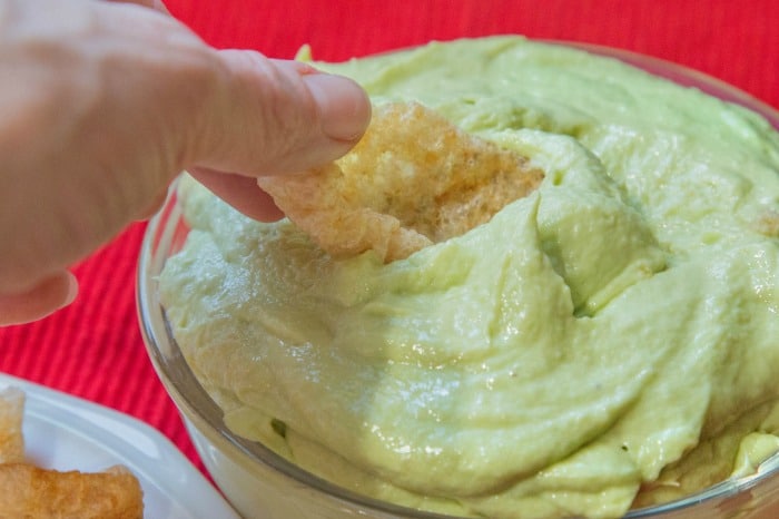 pork rind being dipped into keto avocado cheese dip