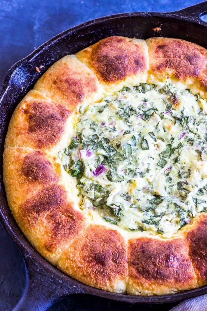 keto spinach dip with pull apart rolls in a cast iron skillet