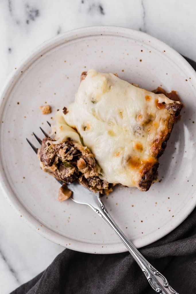 a serving of low carb philly cheesesteak casserole on a plate sliced and a fork