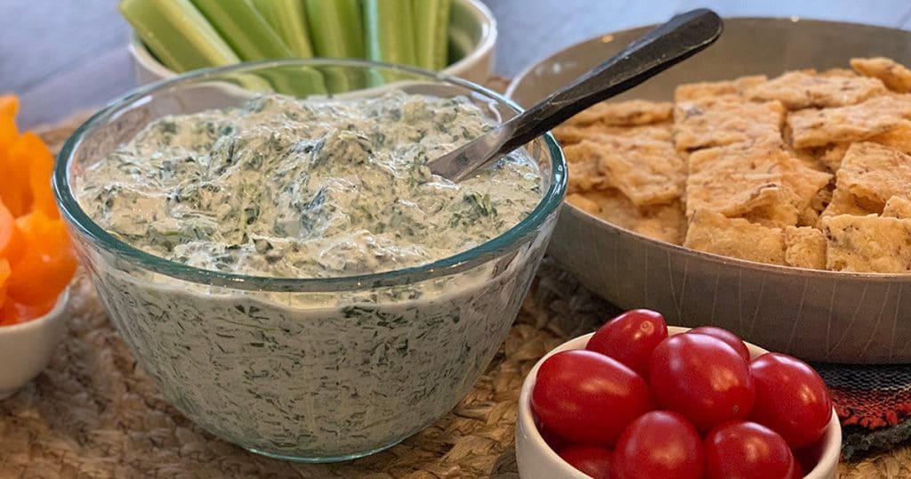 bowl of dill dip surrounded by veggies and low carb crackers