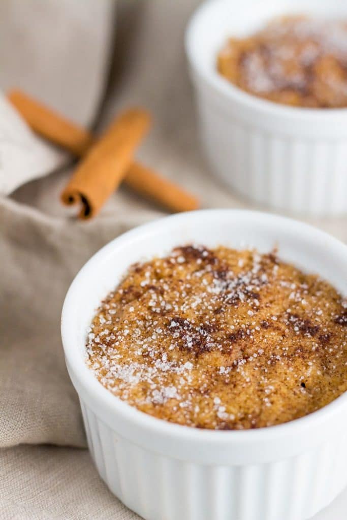 snickerdoodle mug cake in a small dish with cinnamon sticks aside